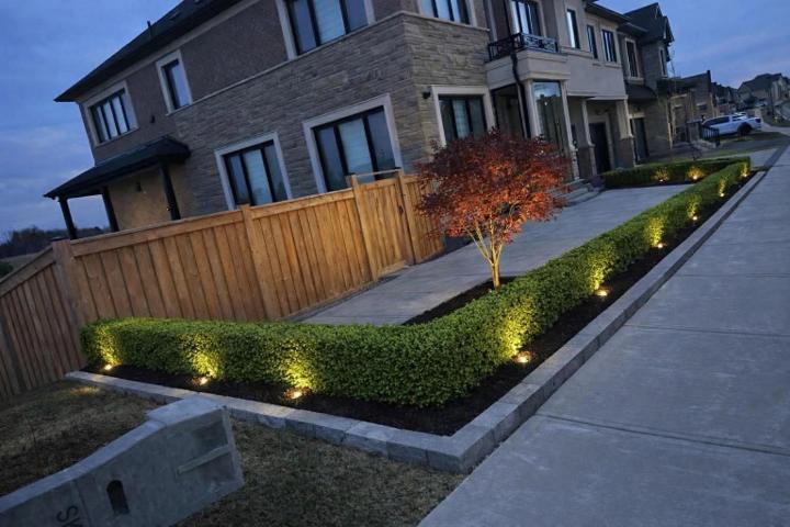 Landscaped garden beds and lawn with low-voltage lighting at dusk