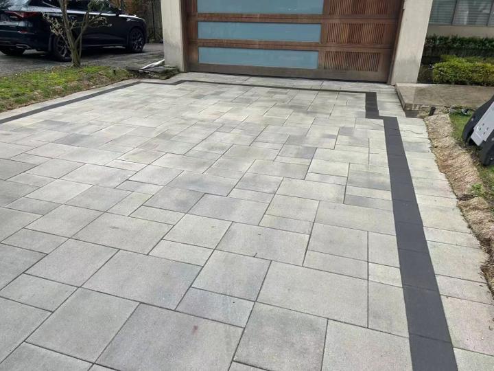 Interlock driveway with a contrasting paver border leading to a modern garage