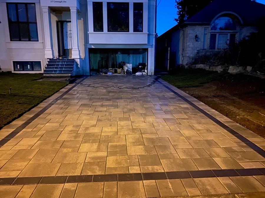 Warm-toned interlock driveway lit at dusk in front of a home