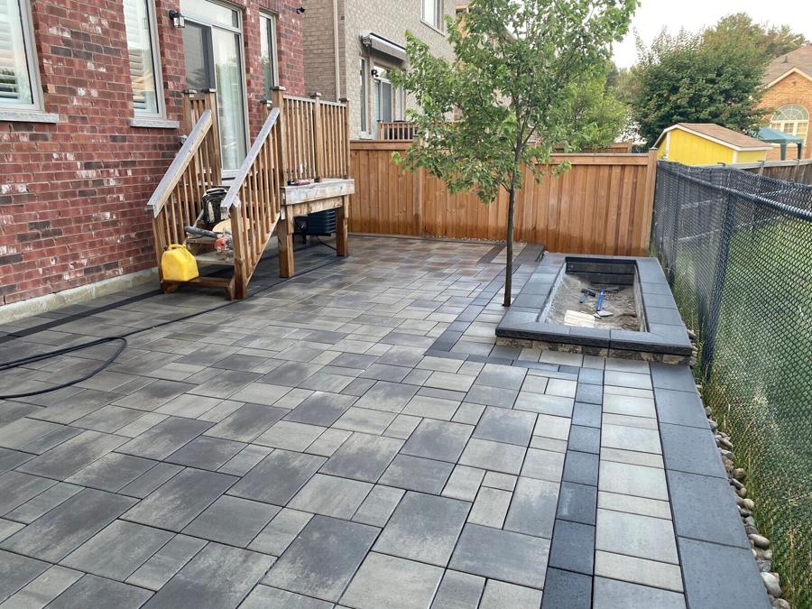 Grey slab patio with a tree planter and steps