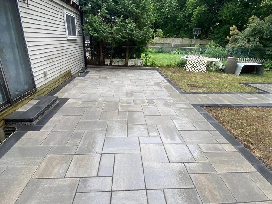 Large-format slab patio running the length of a side yard to a paver walkway