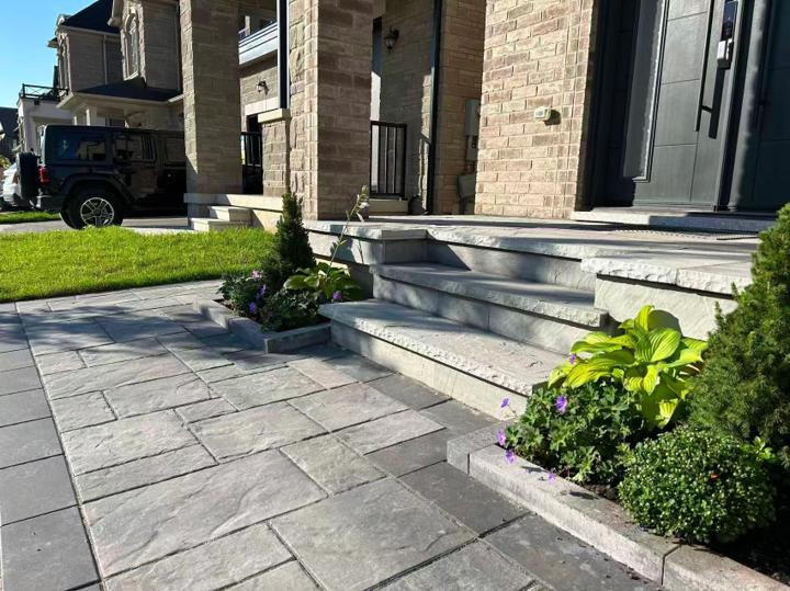 Paver walkway connecting a driveway to broad front entrance steps
