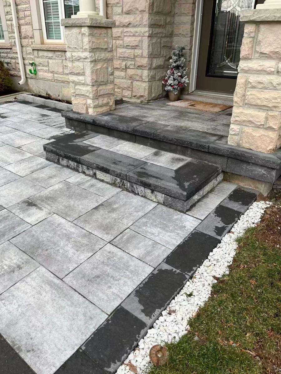 Dark front entrance steps meeting a grey slab walkway with a white gravel border