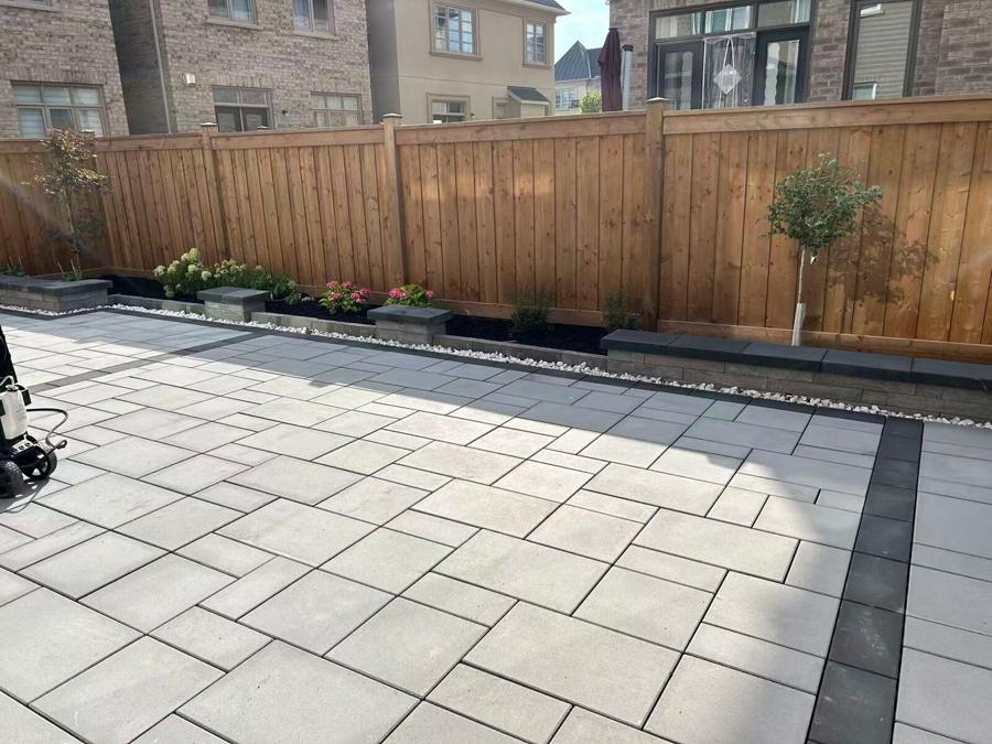 Large paver patio edged by a raised planting bed and a cedar privacy fence