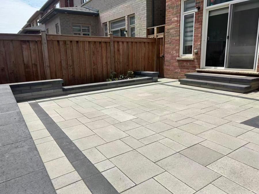 Paver patio with a dark banded border, a raised planter and steps up to the back door