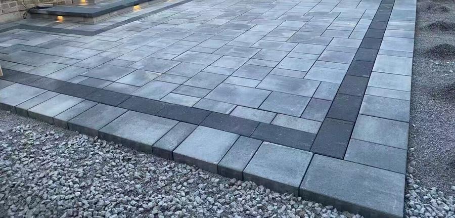 Grey paver patio with a charcoal border and steps along the far edge