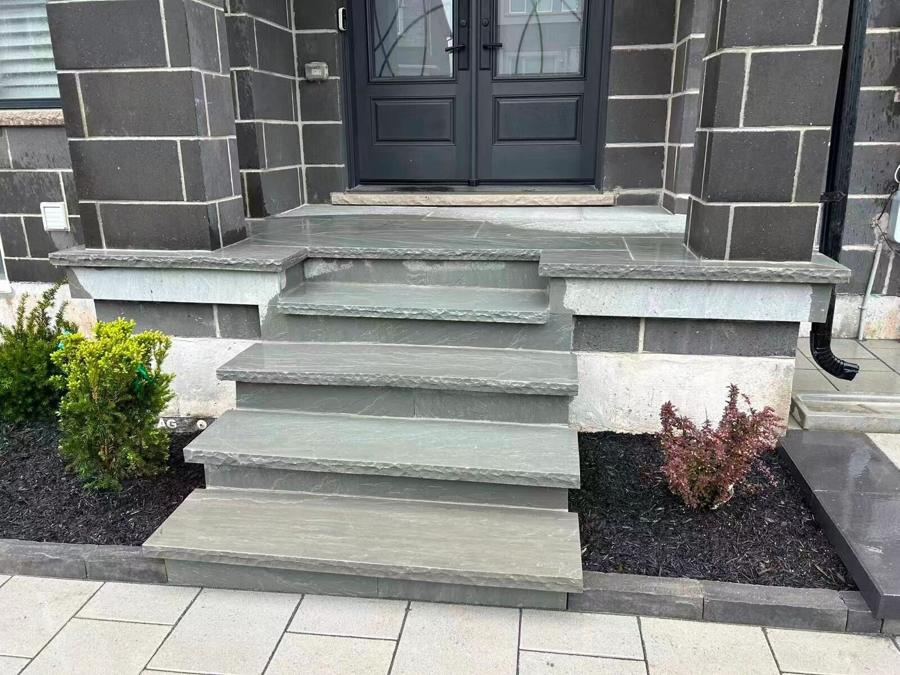 Grey natural-stone entrance steps beside a planting bed