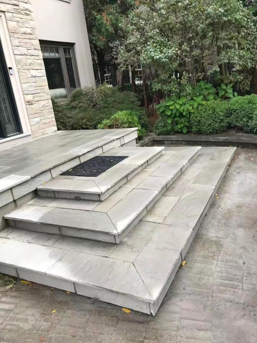 Tiered natural-stone steps leading up to a paver patio
