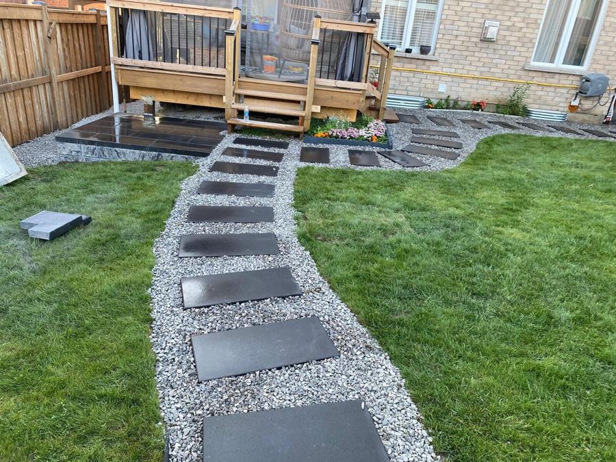 Cedar deck overlooking a dark stepping-stone path and fresh sod lawn