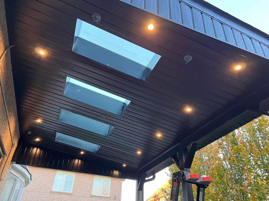 Black pergola with skylights, lit at dusk