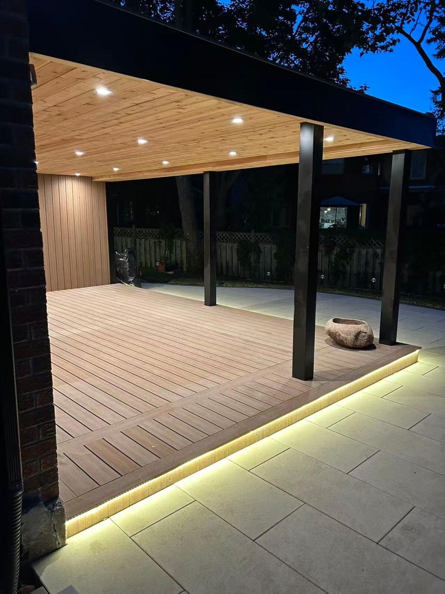 Covered composite deck at dusk with a cedar-clad ceiling, pot lights and an LED strip along the edge