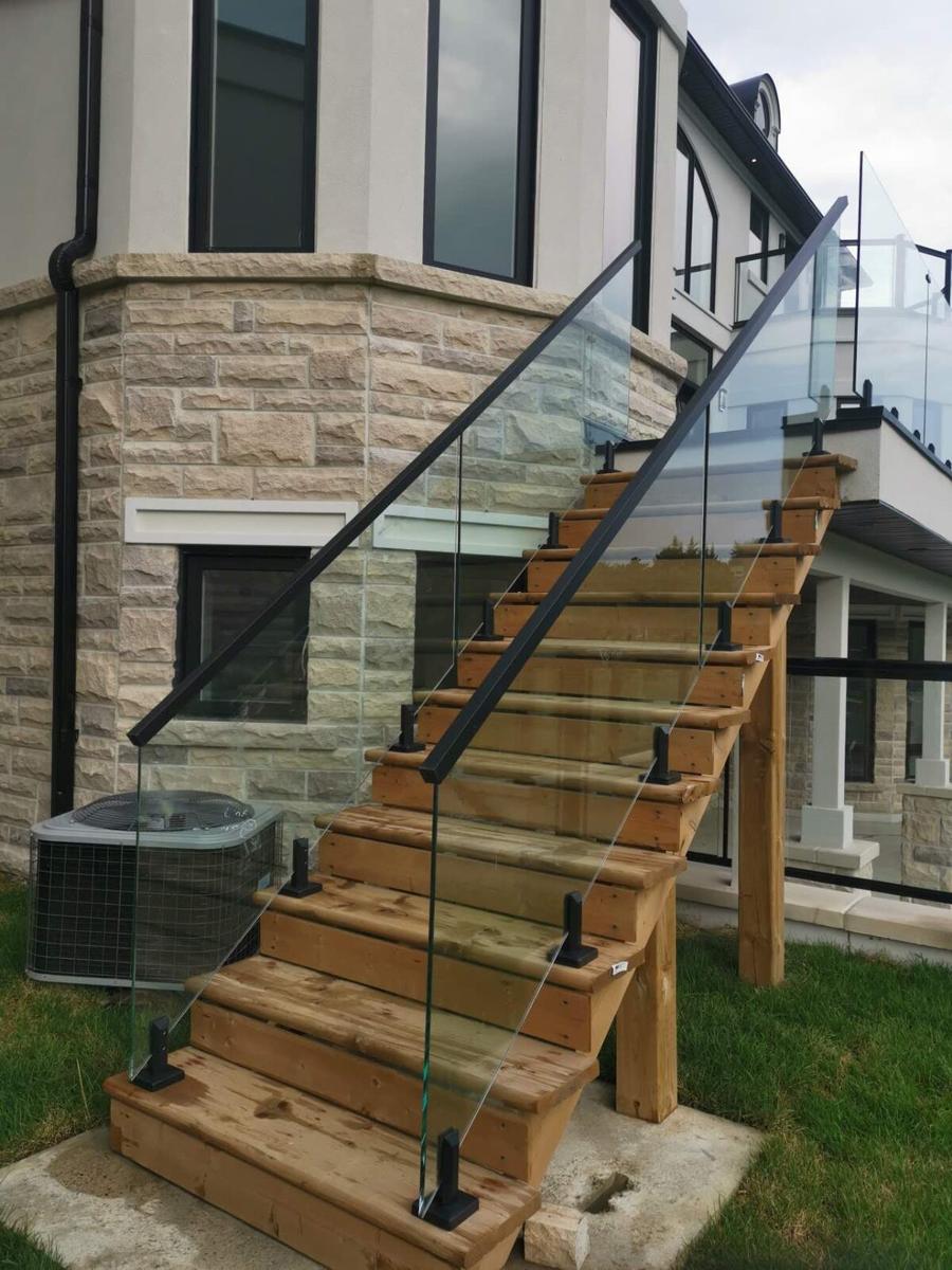 Cedar stairs with a glass railing running down beside a stone-clad house