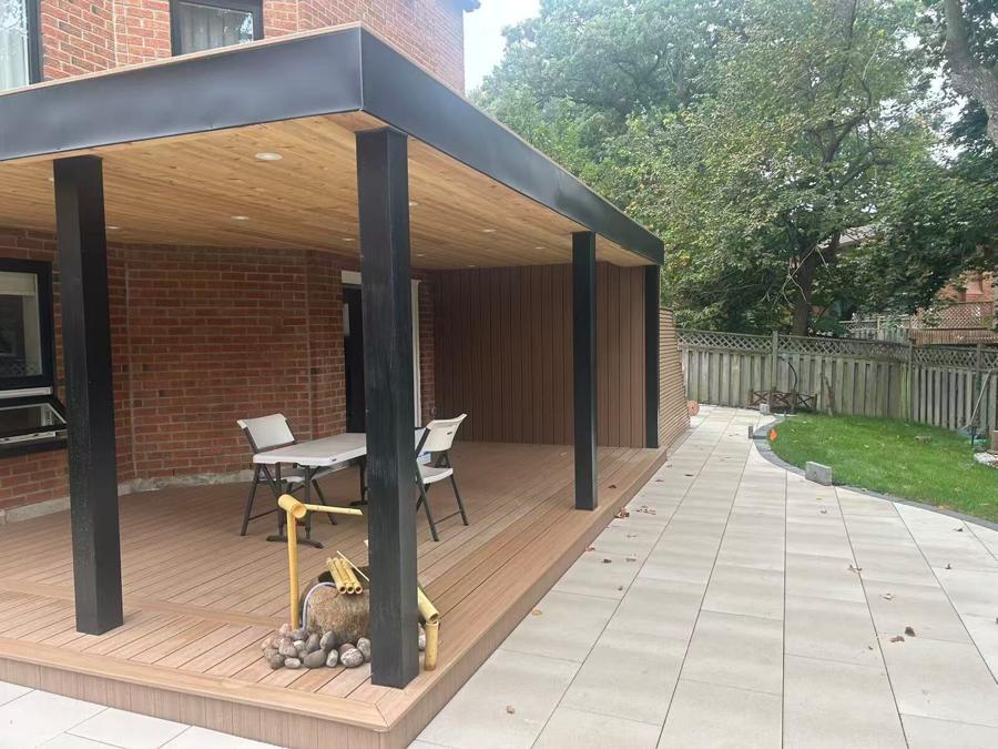 Flat-roofed pavilion over a composite deck, opening onto a wide slab patio