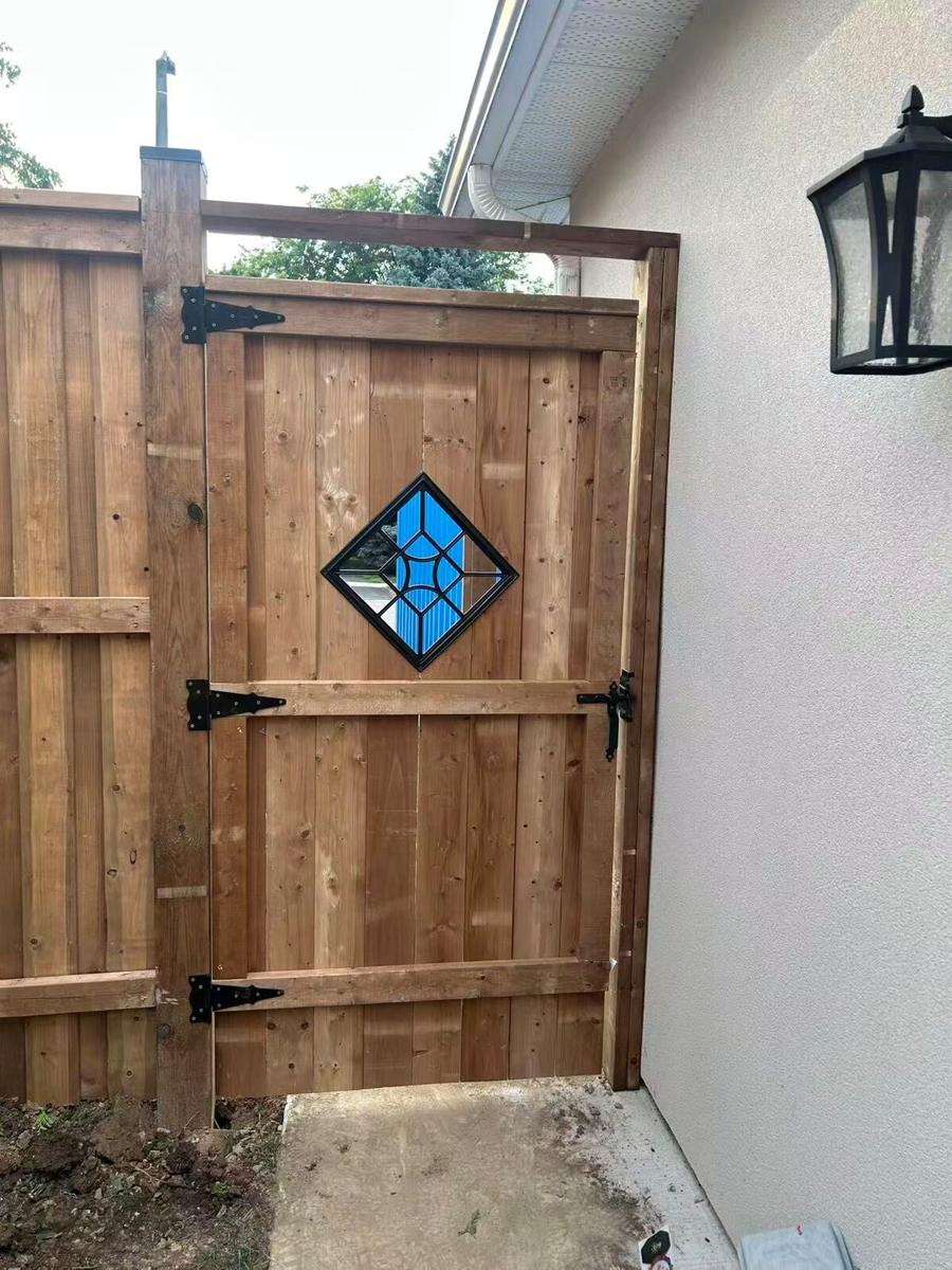 Cedar privacy gate with black strap hinges and a stained-glass diamond insert