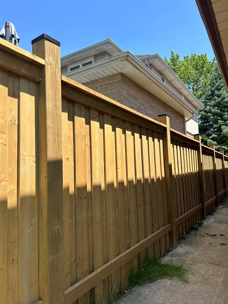 Wood privacy fence along a gravel side passage beside a house