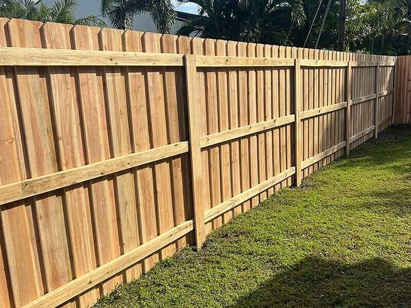 Wood privacy fence with horizontal support rails along a lawn