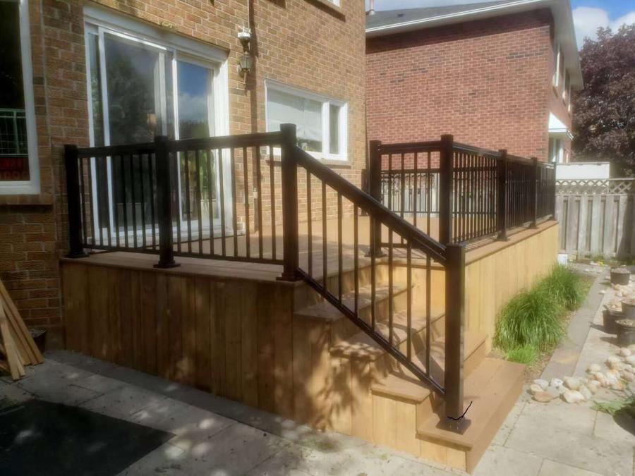 Cedar deck with a dark aluminum railing, steps down to a flagstone path and ornamental grasses